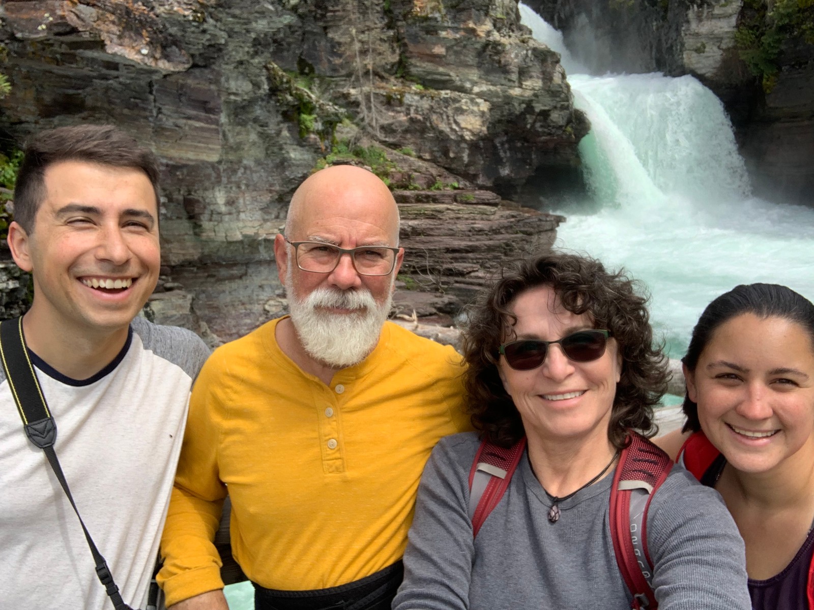 a group of people posing for a photo in front of a waterfall