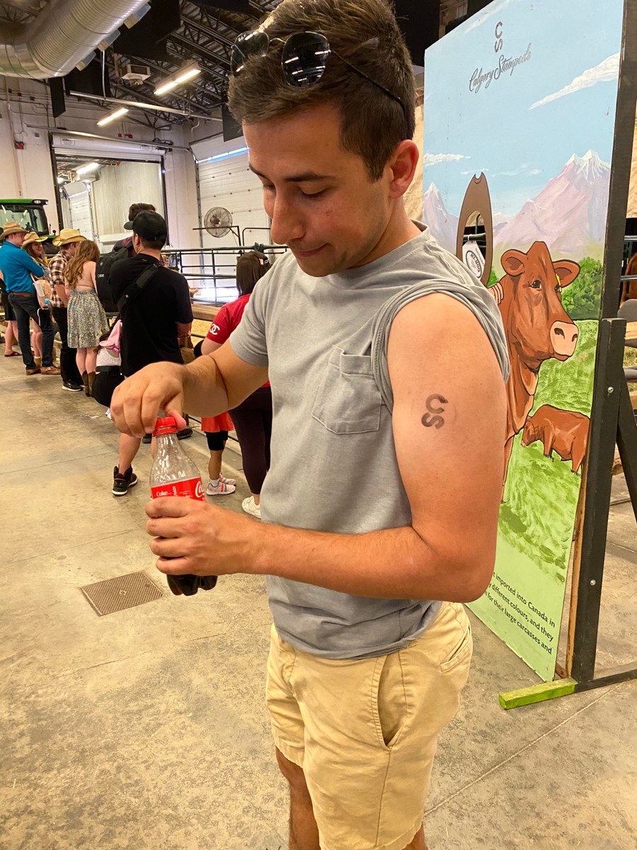 a person with a tattoo on the arm holding a bottle of soda
