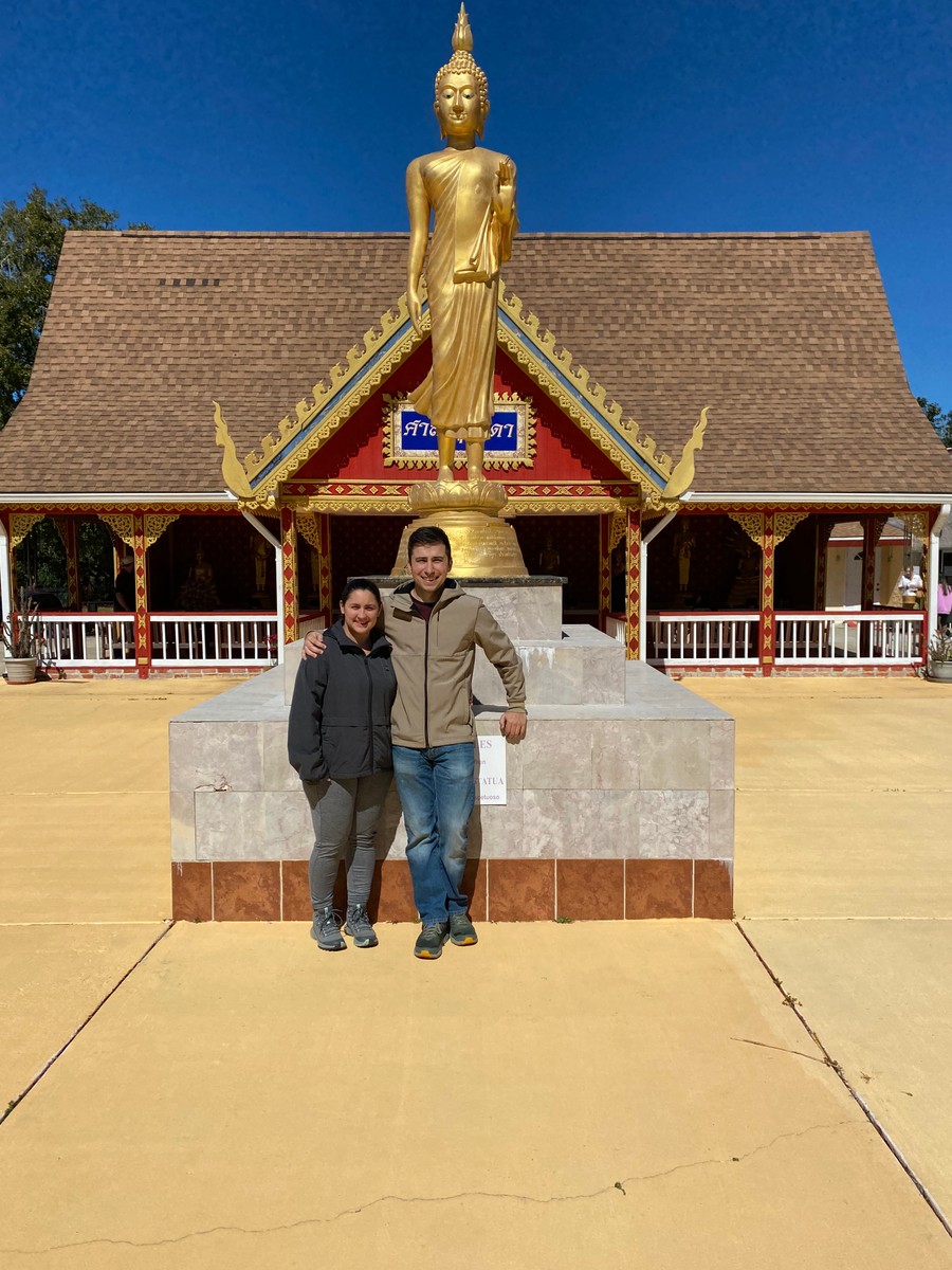 a man and woman posing in front of a statue