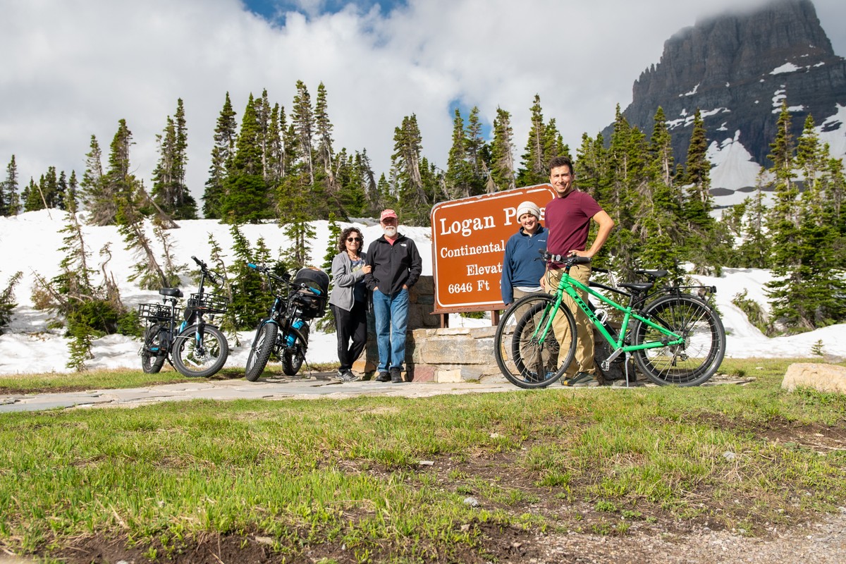 a group of people standing next to a sign and a bicycle