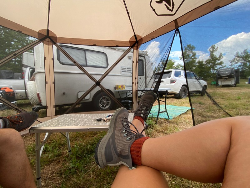 a person's legs and feet in front of a tent