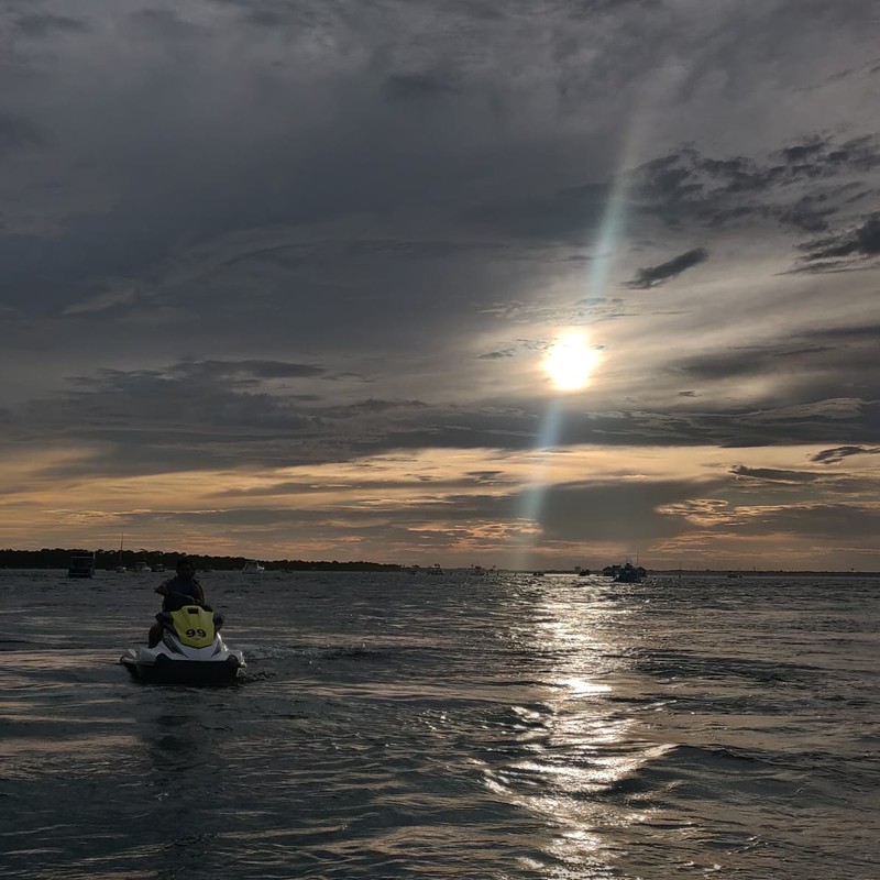 a person in a small boat in the water with the sun setting