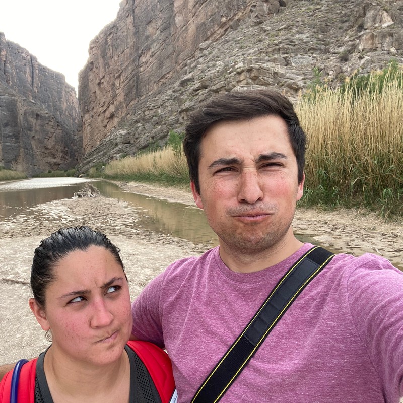 a man and woman taking a selfie in front of a rocky cliff