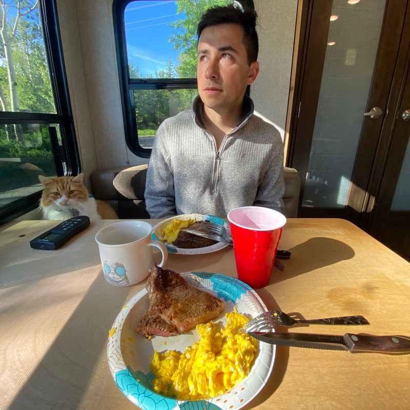 a person sitting at a table with food and drinks