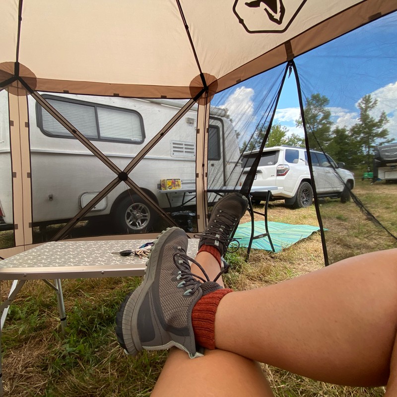 a person's legs and feet in front of a tent