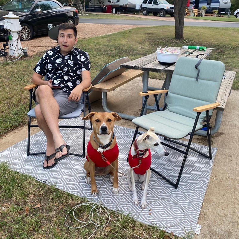 a person sitting outside with two dogs