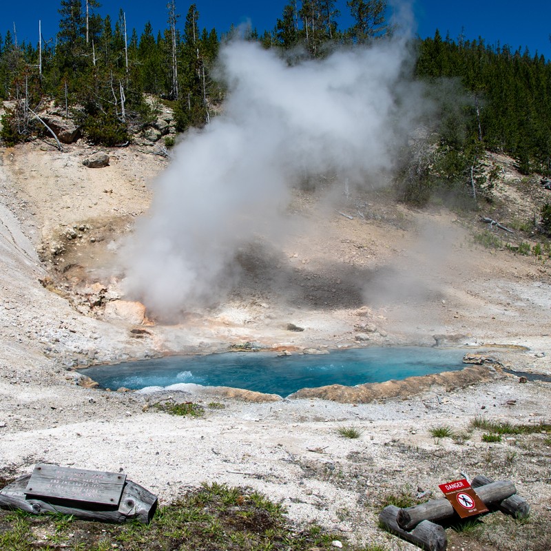 a geyser spewing water into a small pool of water