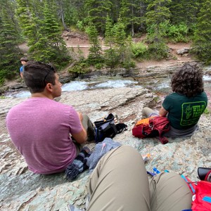 a group of people sitting on a rock looking at a river