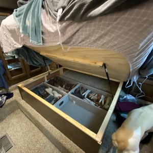 a wooden box with a lid and a white dog next to it