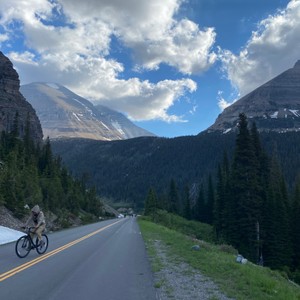 a person riding a bicycle on a road in the mountains