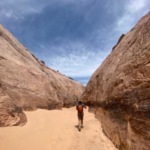 a man walking on a sandy path between large rocks