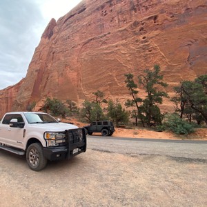 a white truck parked in front of a red rock cliff