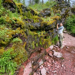 a man taking a picture of a rocky hillside