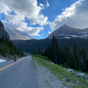 a person riding a bicycle on a road in the mountains