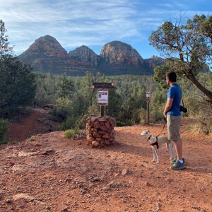a man and a dog on a trail with a sign and mountains in the background