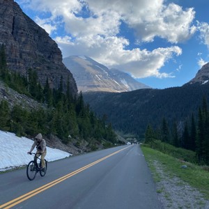 a person riding a bicycle on a road in the mountains