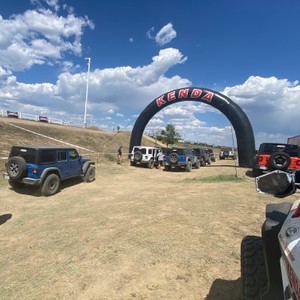 a group of cars parked on a dirt road with a large arch