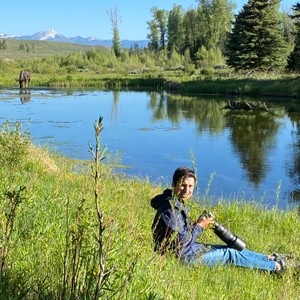 a person sitting on grass by a lake