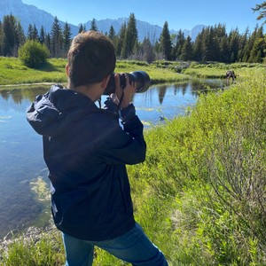 a man taking a picture of a lake with a dog