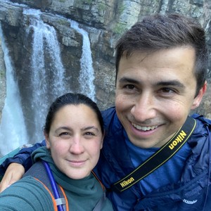 a man and a woman taking a selfie in front of a waterfall