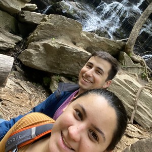 a man and woman taking a selfie in front of a waterfall