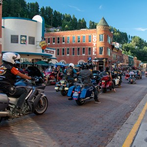 a group of motorcyclists ride down a street