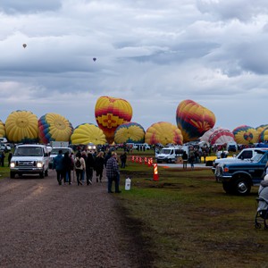 a group of people standing next to a road with hot air balloons