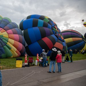 a group of people standing next to a group of hot air balloons