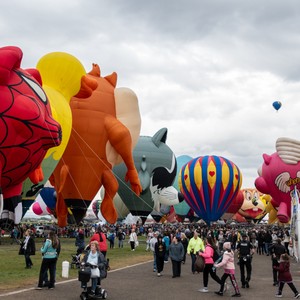 a group of people walking with hot air balloons