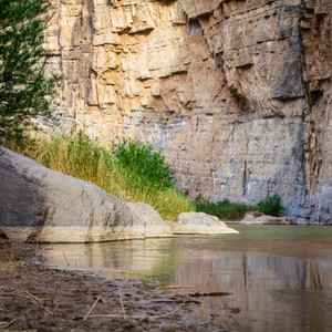 a body of water with a rock wall and grass