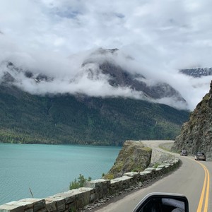 a road next to a body of water with mountains in the background