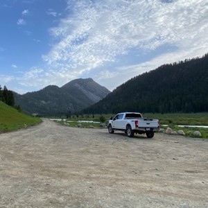 a white car on a road with mountains in the background