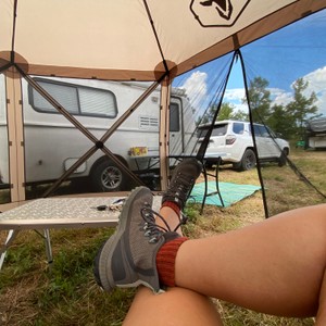 a person's legs and feet in front of a tent