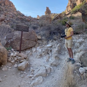 a man taking a picture of a sign in a rocky area