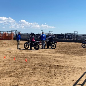 a group of people standing next to motorcycles on a dirt field
