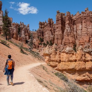 a man walking on a dirt road with Bryce Canyon National Park in the background
