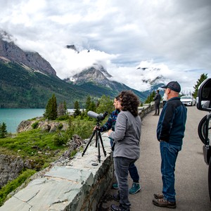 a man and woman looking at a camera on a path by a lake