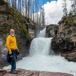 a man standing next to a waterfall