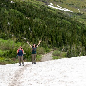 a couple of people on a snowy mountain with trees in the background