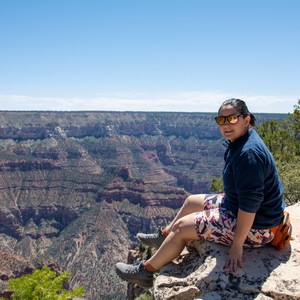 a man sitting on a rock overlooking a canyon