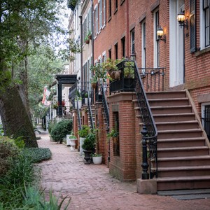 a brick walkway with a brick building and trees with Beacon Hill in the background